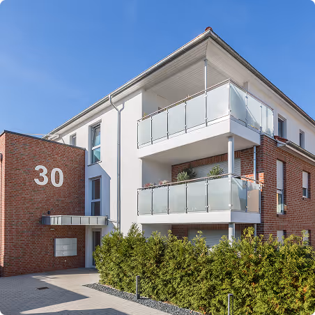 Modernes Wohngebäude mit zwei Balkonen und Hausnummer 30 an der Backstein- und Putzfassade.