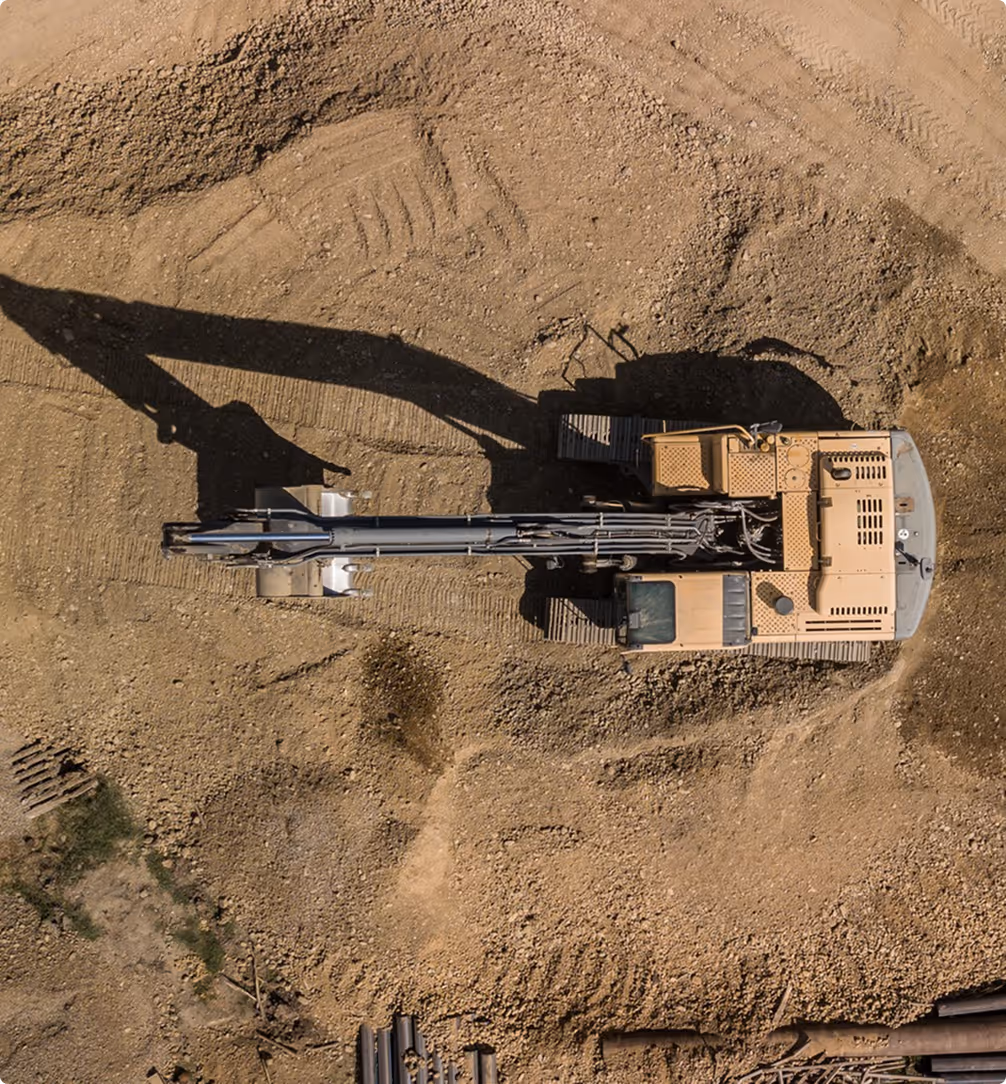 Luftaufnahme eines großen Baggers mit ausgebreitetem Arm auf einer Baustelle.
