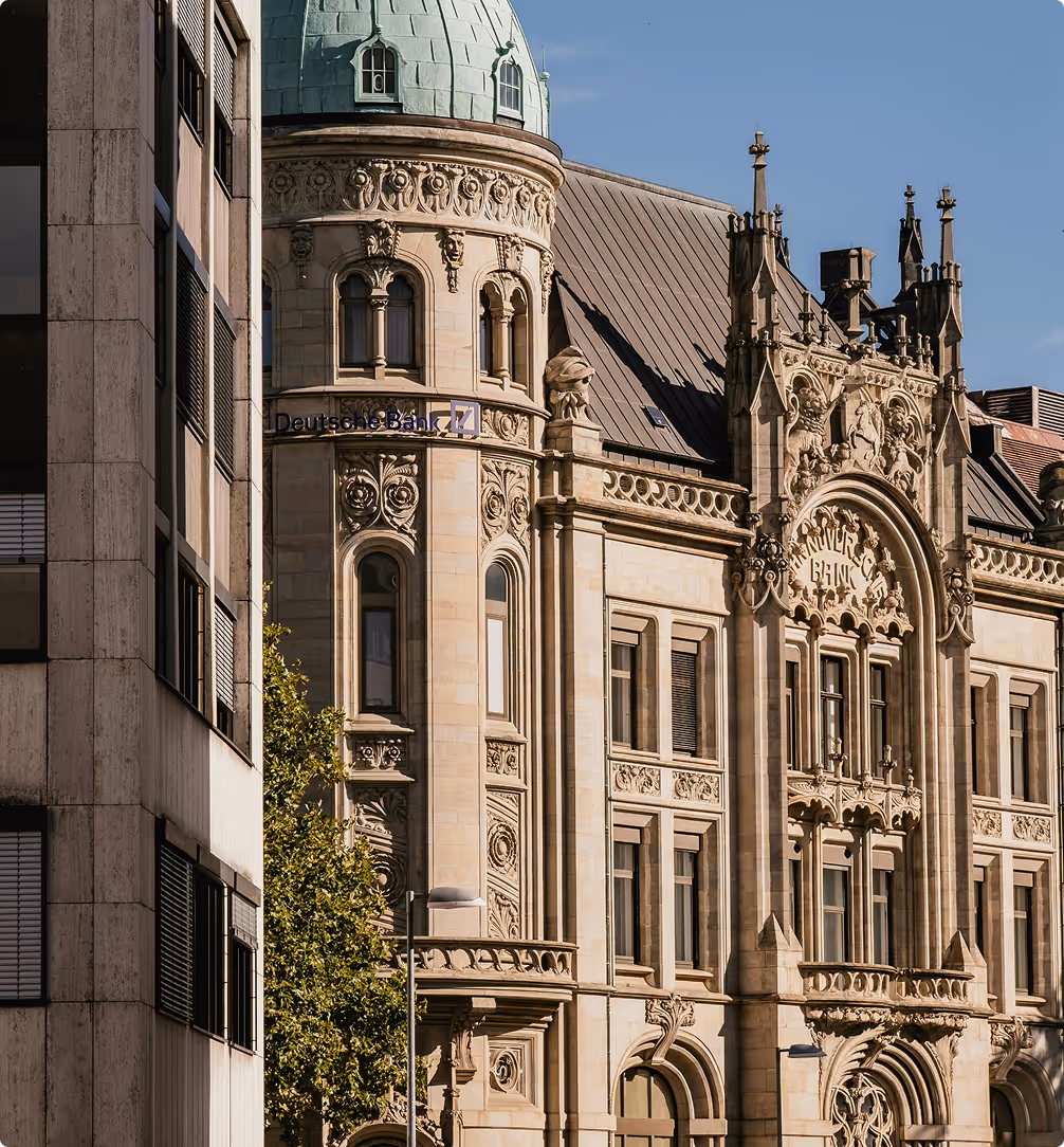 Historisches Gebäude mit einer turmartigen Fassade und dem Schriftzug Deutsche Bank am Himmel.
