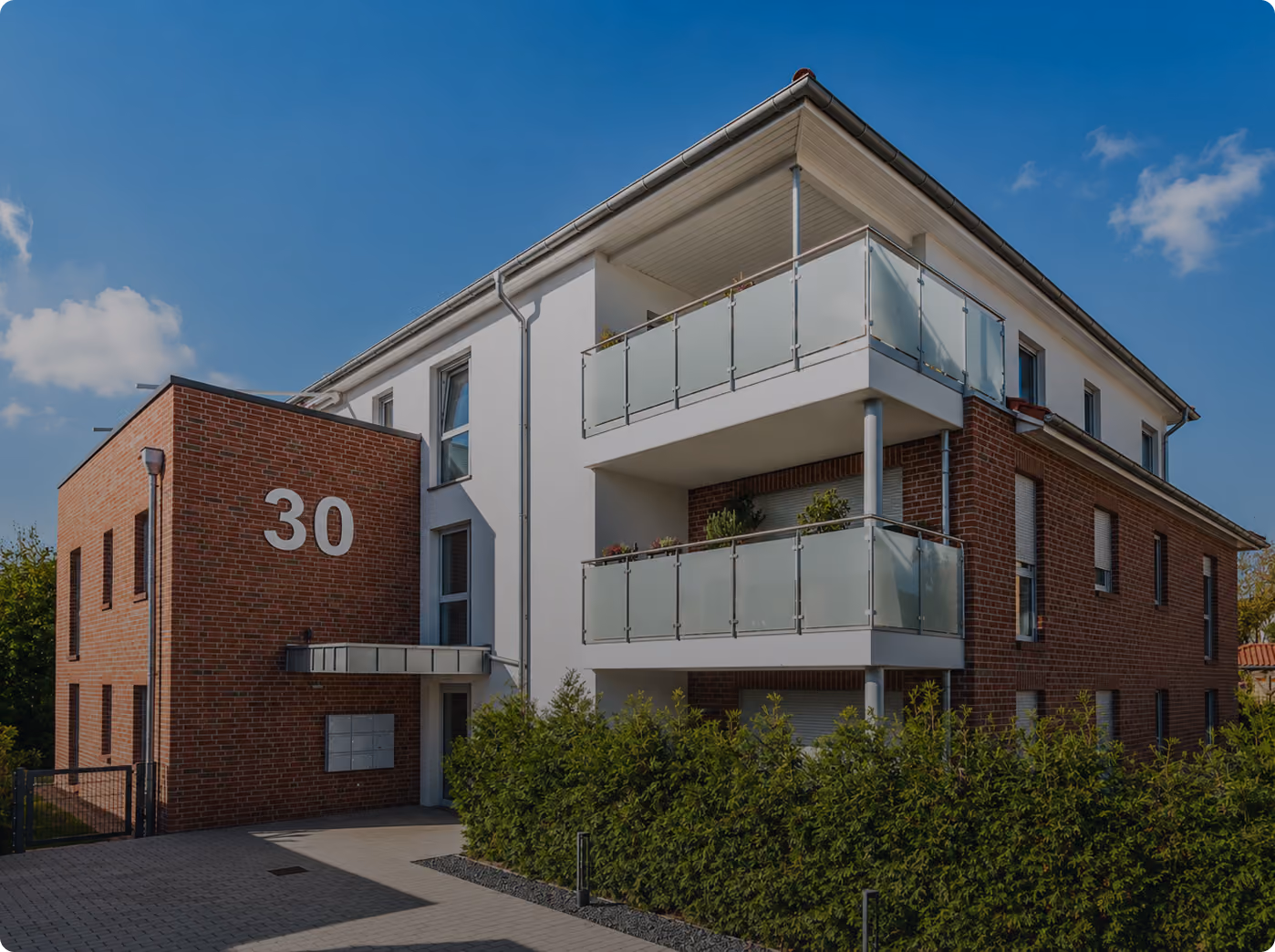Modern apartment building with brick and white walls, balconies, and large number 30 on facade.