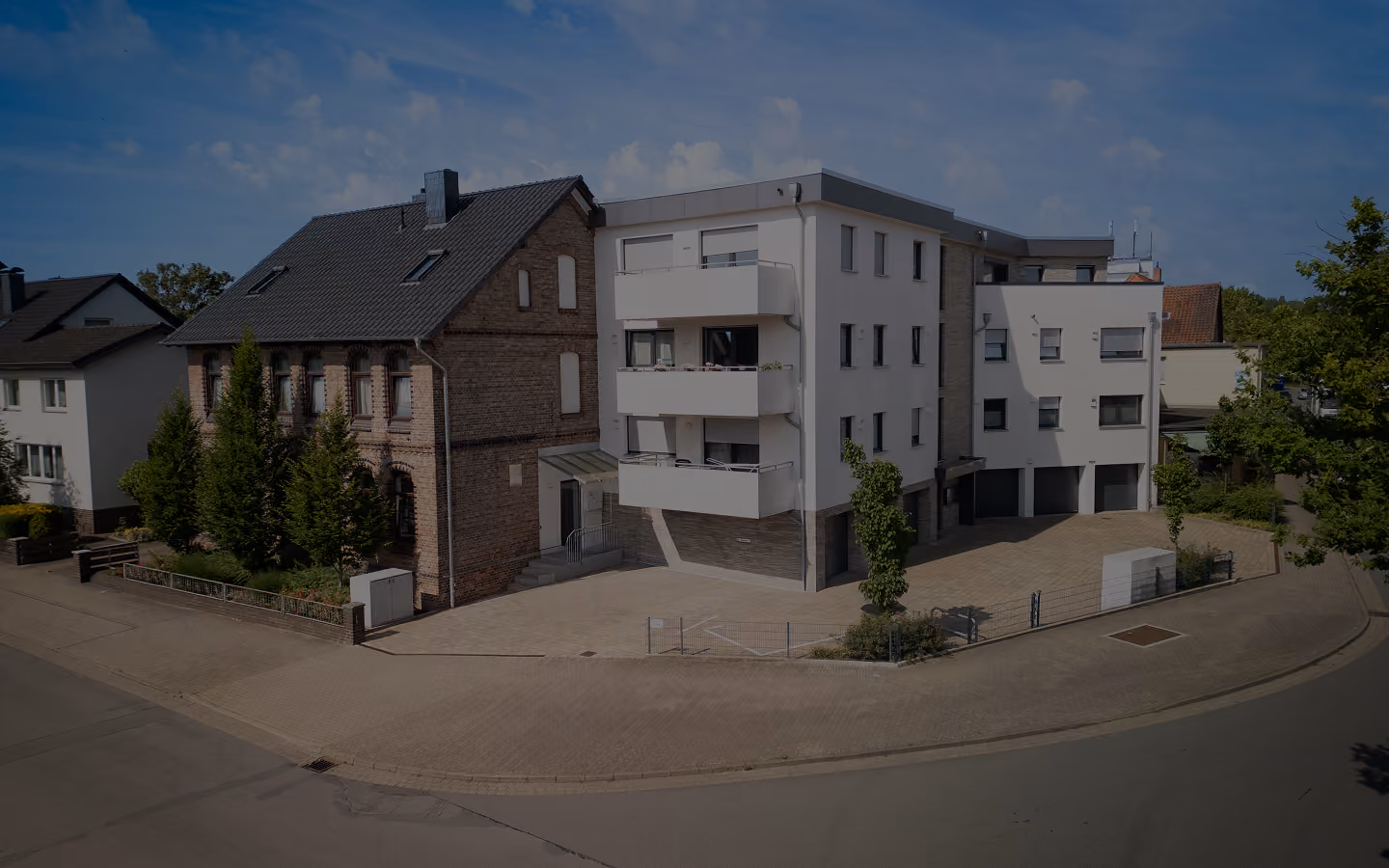 Ein Gebäude mit traditionellem Backstein- und modernem weißem Teil an einer Straße.