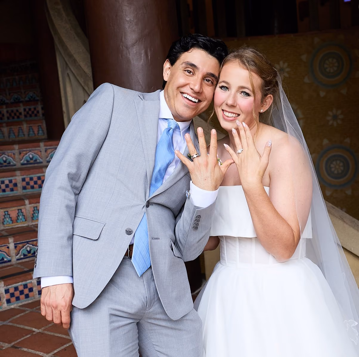 Newly wed young couple showing off the rings in a professional wedding photo at the Santa Barbara courthouse.