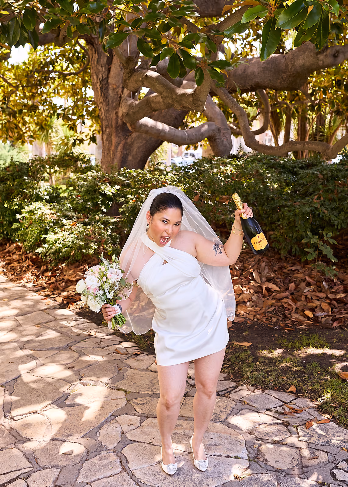 Asian bride with champagne bottle clowning around at the Santa Barbara courthouse.