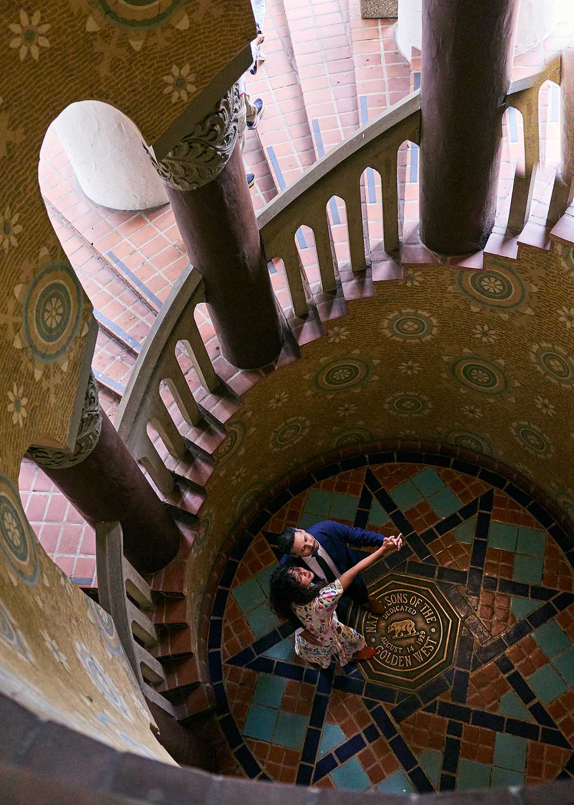 Bride and groom dancing near the California seal in the bottom of the Santa Barbara Courthouse spiral staircase.
