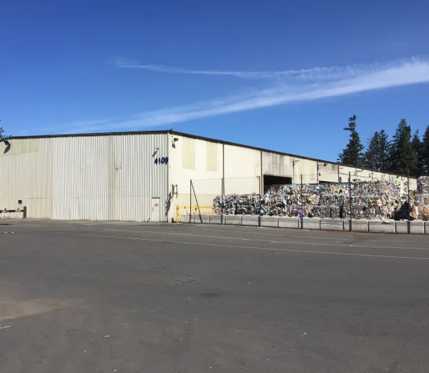 Large recycling facility exterior with piles of sorted commercial and residential recyclable materials.