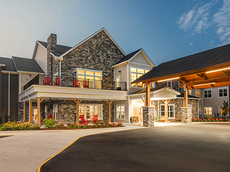 Stone and wood building with porch, red chairs, and covered entrance lit at twilight.