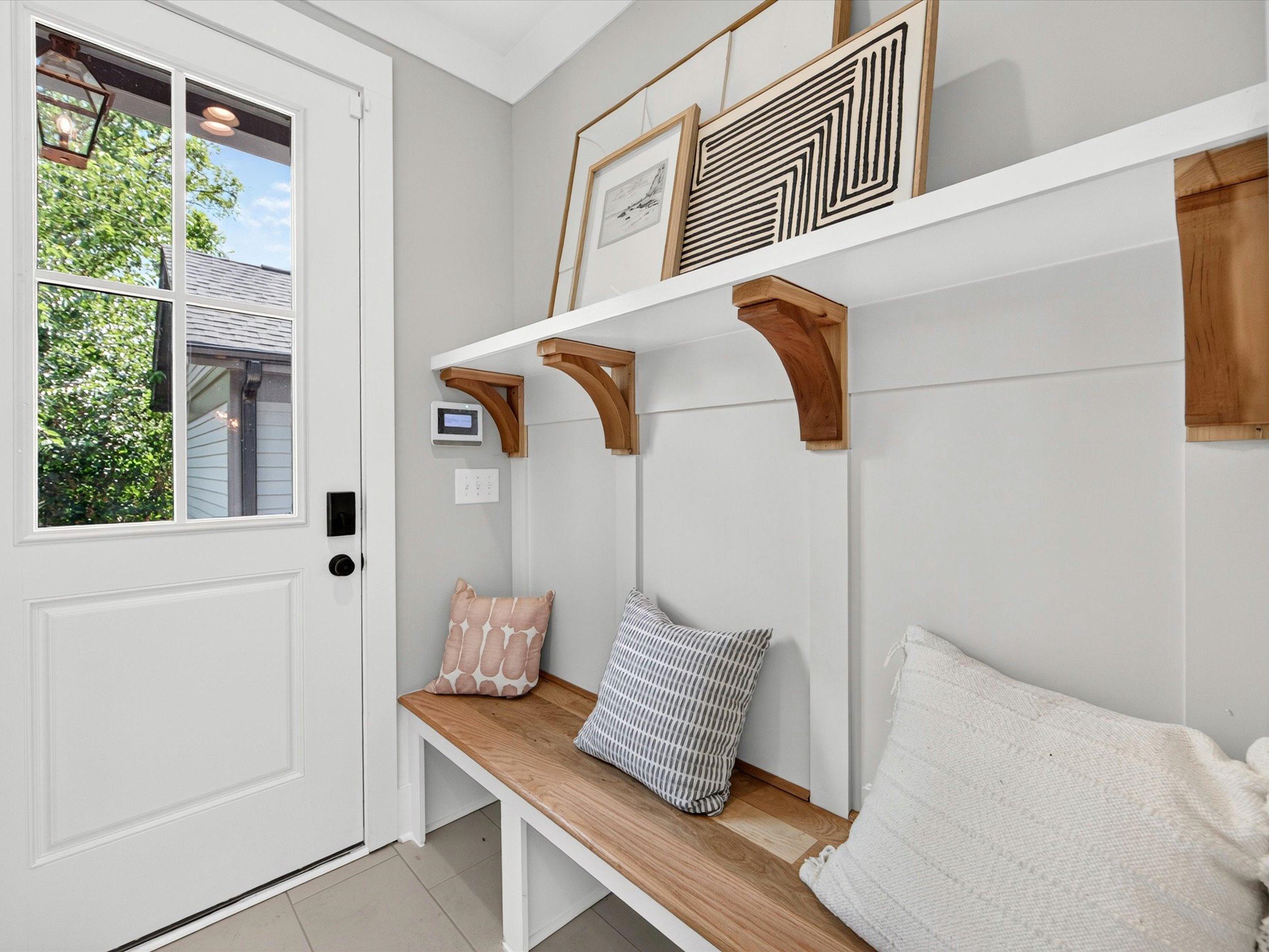 Side entry with a half-glass door, a built-in wood bench, and a white shelf with wood brackets
