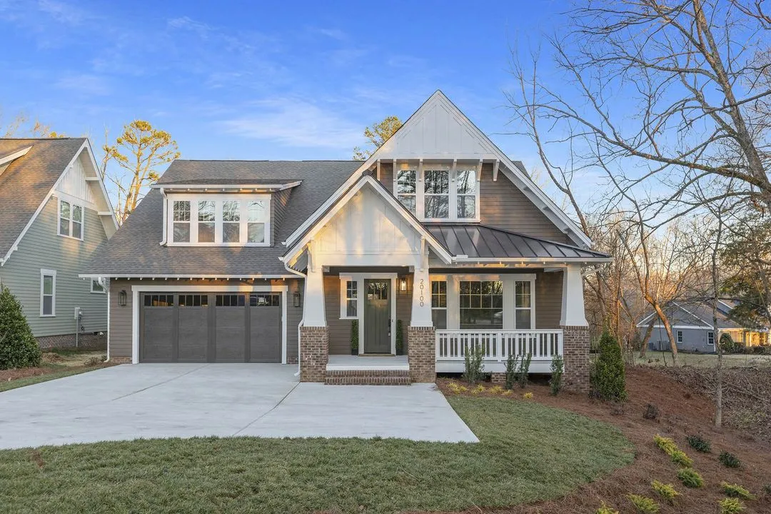 Craftsman-style home with a front porch, cedar-shake gable, stone-and-brick columns, and a two-car garage