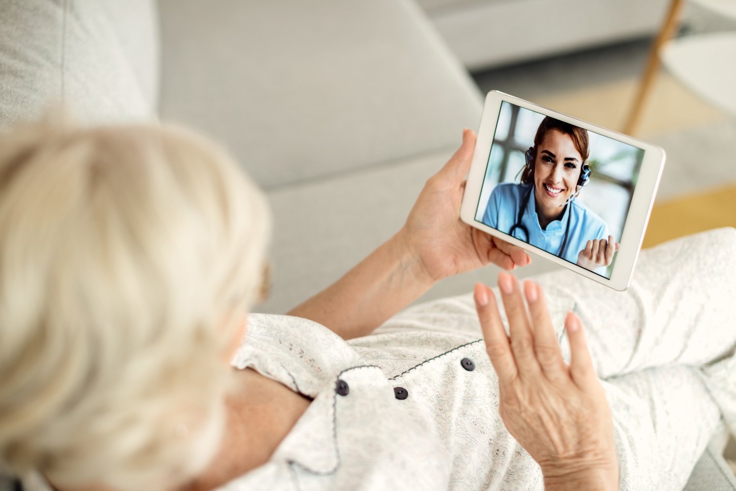 A senior on a video call with a smiling registered nurse