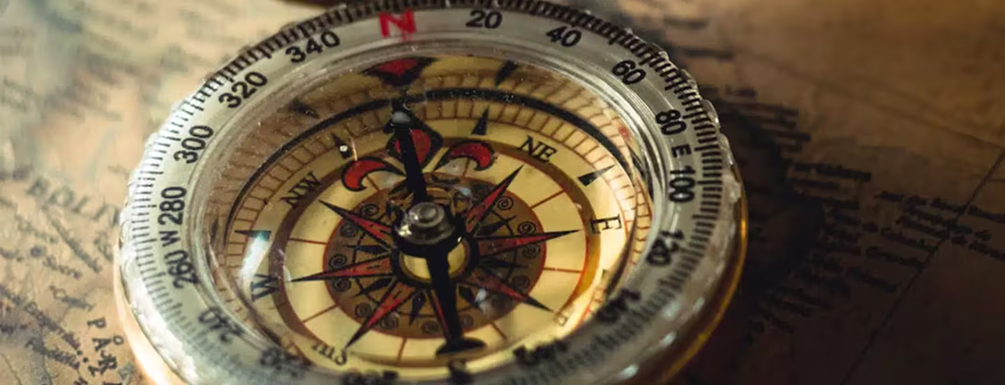 Image of an old compass on top of a wooden table