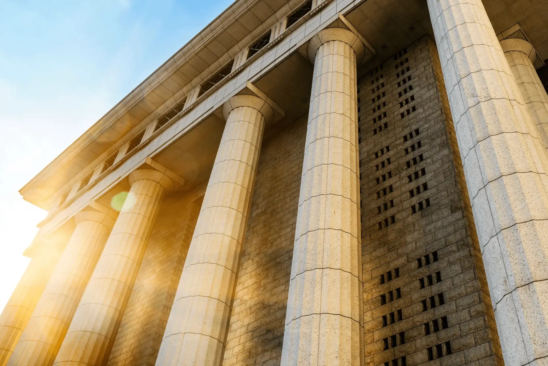 Sunlight streaks across the tall marble columns of a federal courthouse building.