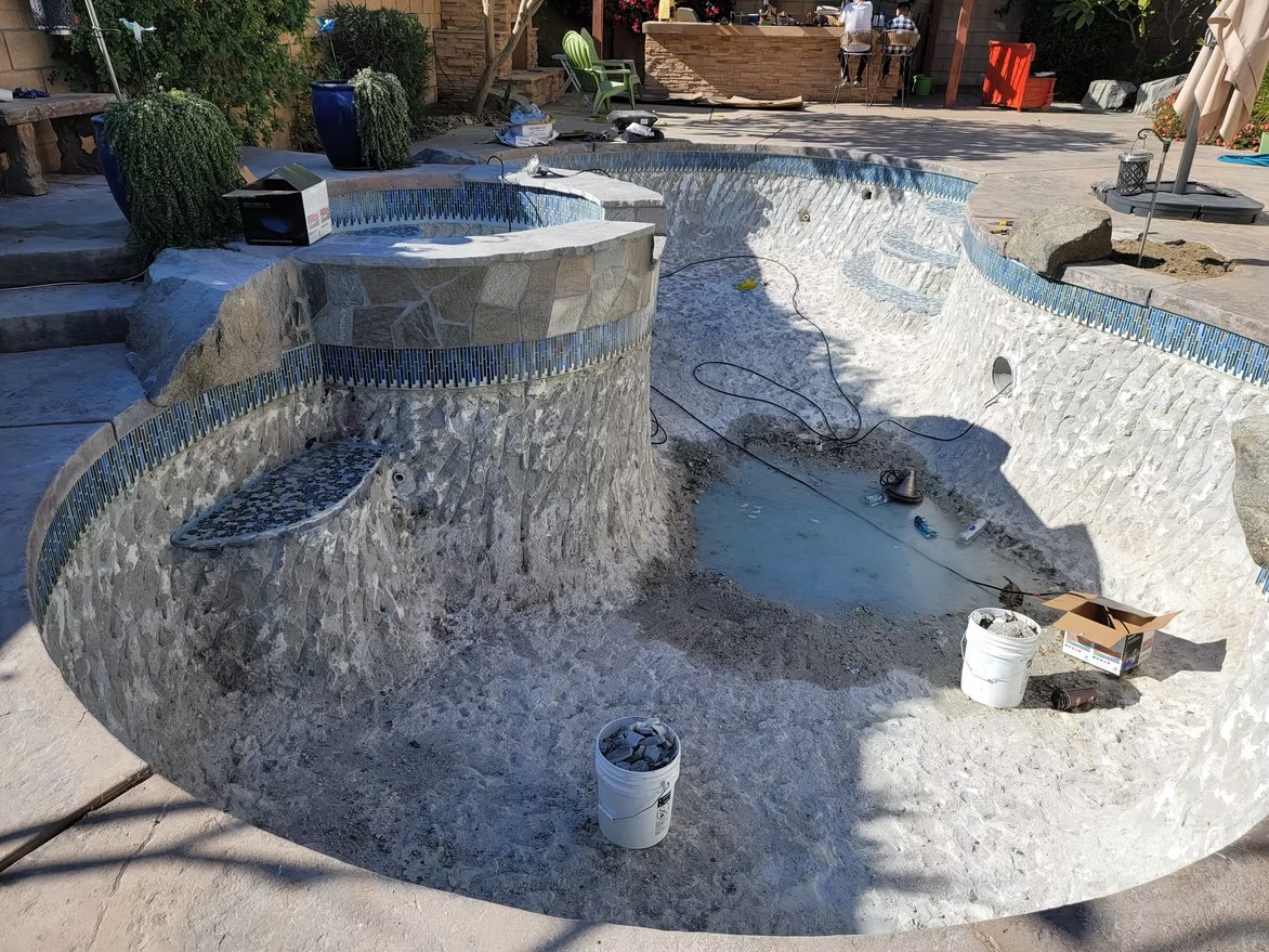 Pool under construction with a stone wall and new tile work