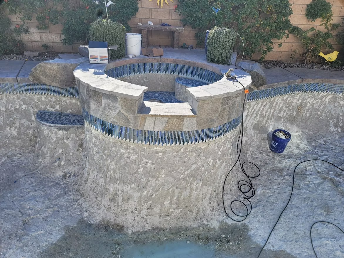 Raised spa with new blue waterline tile being installed