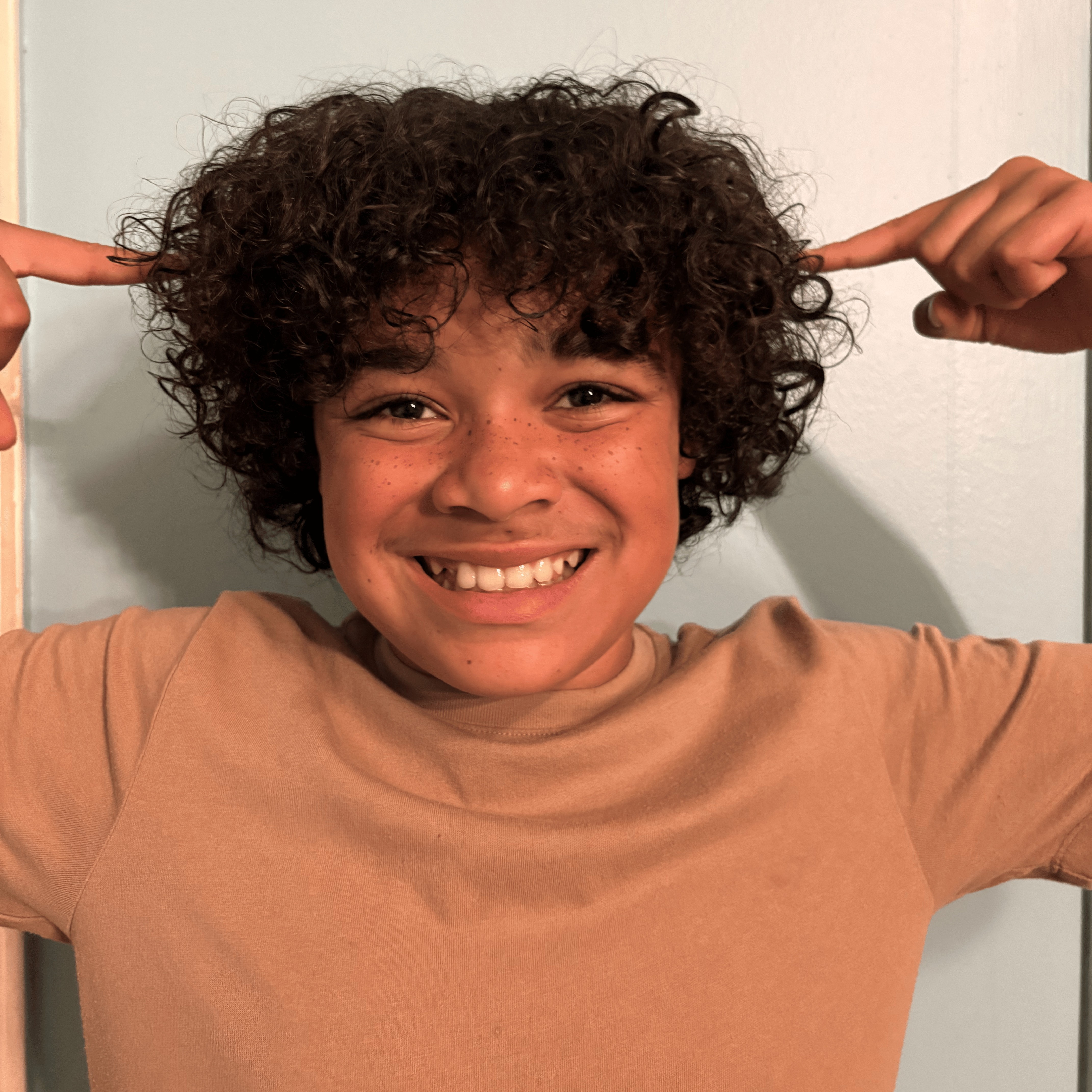 Curly-haired kid happily pointing to their curls