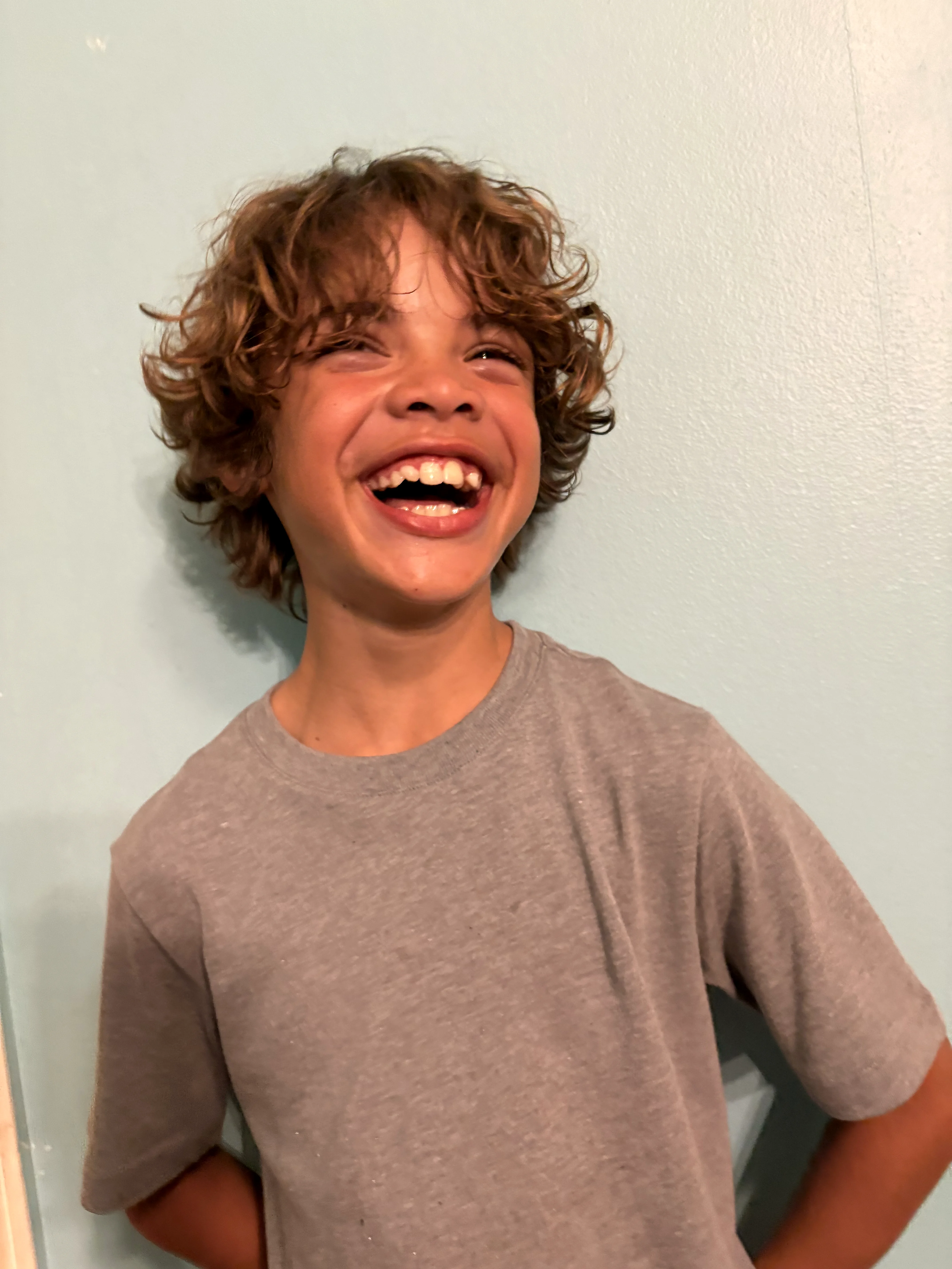 Grinning boy pointing at his curly hair with both hands
