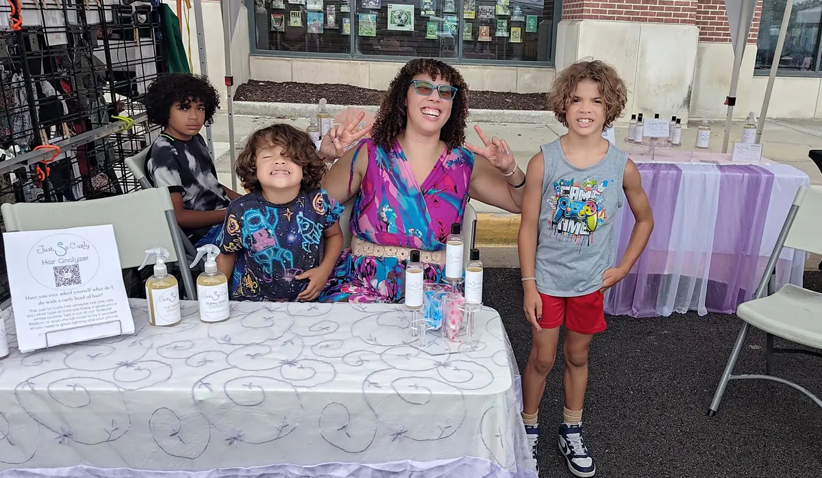 Cassandra, founder of Just So Curly, with her family at the Just So Curly table during an Oak Park Mall pop-up