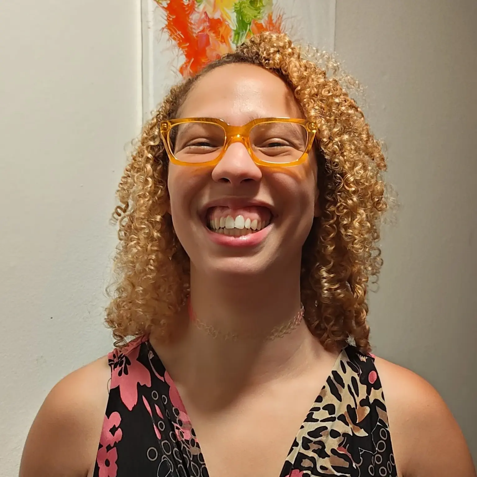Two curly-haired kiddos hugging and smiling against a light blue wall