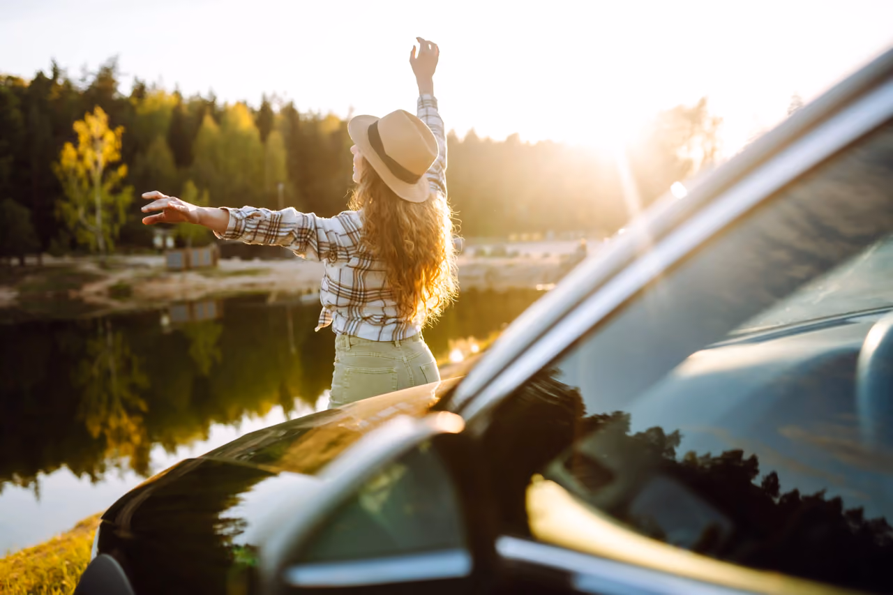 Driver enjoying the view beside their car on a sunny day
