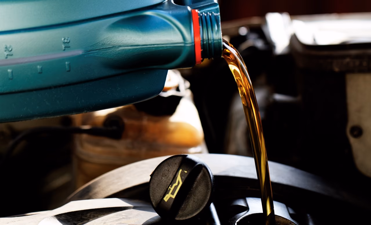 Fresh engine oil being poured into a car engine during a mobile car service