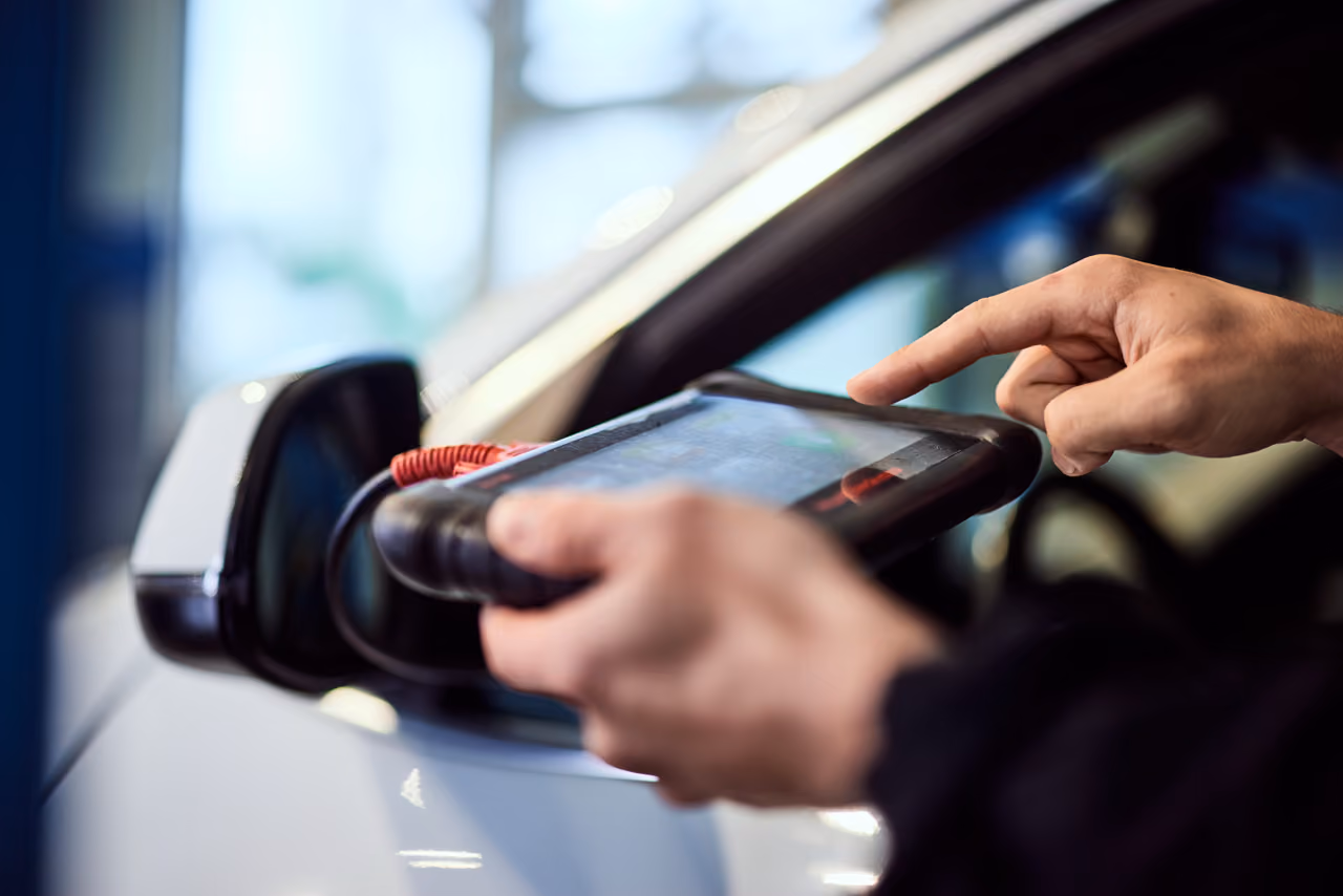 Mechanic using a handheld diagnostic scanner to read car fault codes