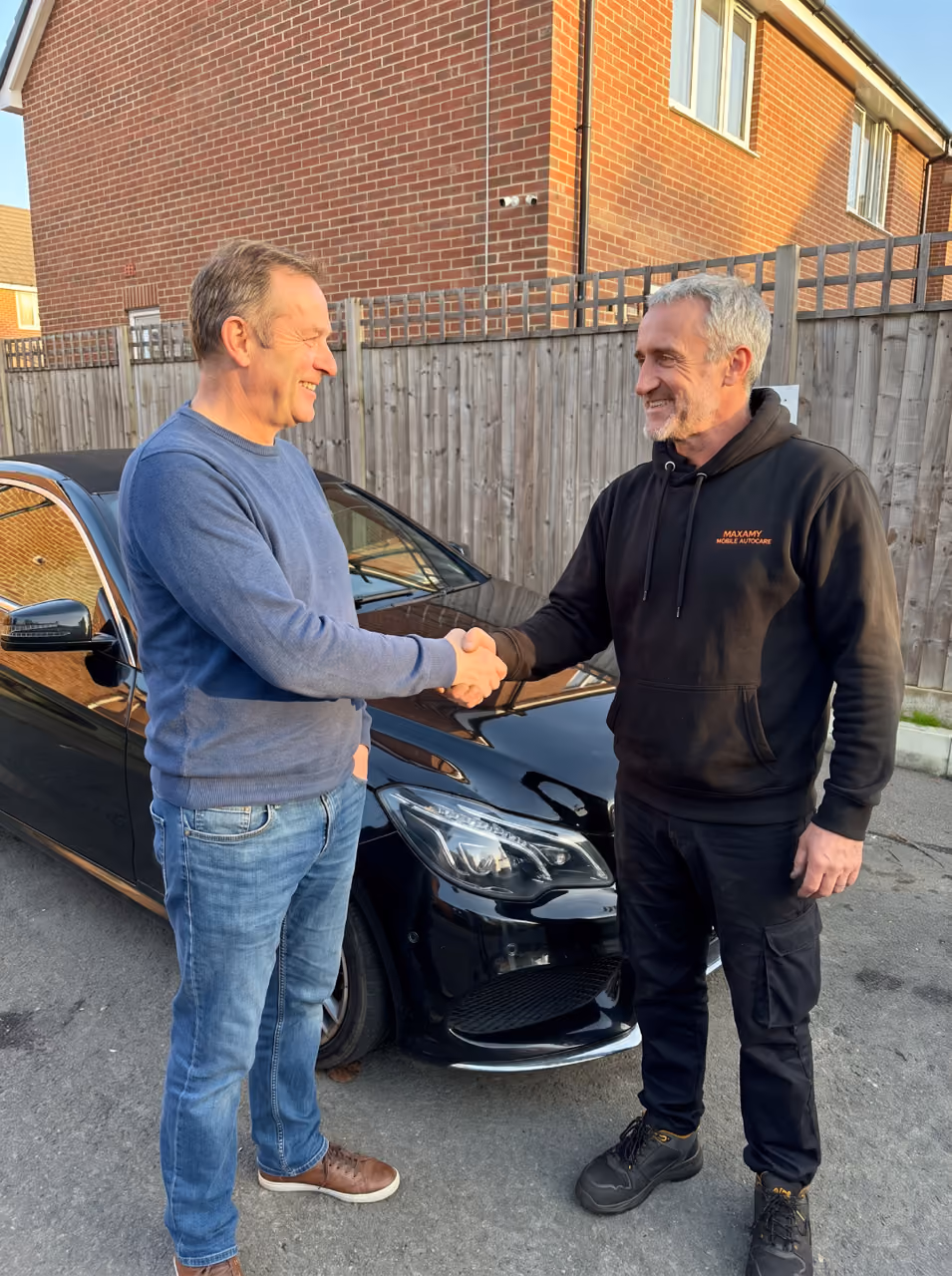 A satisfied customer shaking hands with his mobile mechanic after a Mercedes repair