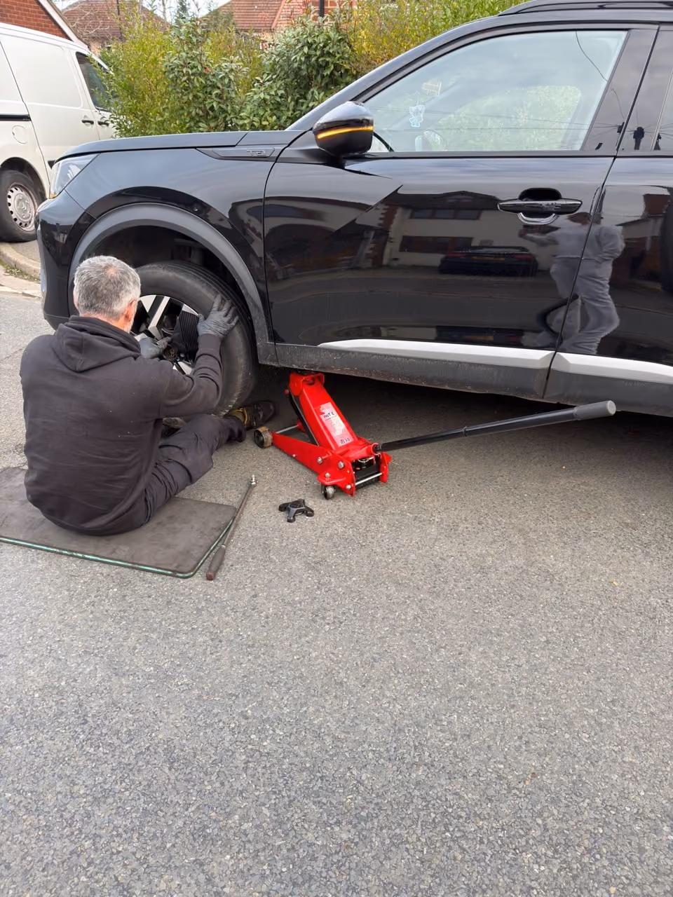 Mobile mechanic repairing the brakes on a black SUV on a customer's driveway in Slough
