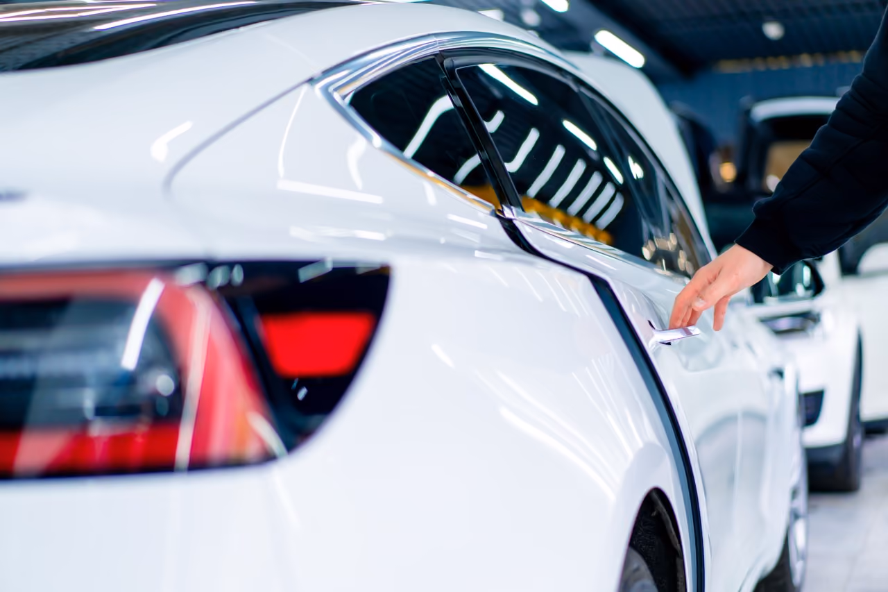 Mechanic opening the door of a white car during a bodywork check
