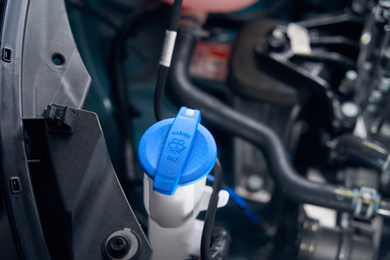 Blue screenwash reservoir cap in a car engine bay