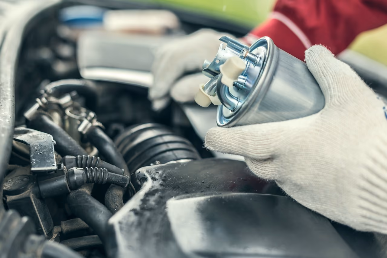Mechanic replacing a fuel filter in the engine bay during a fuel system repair