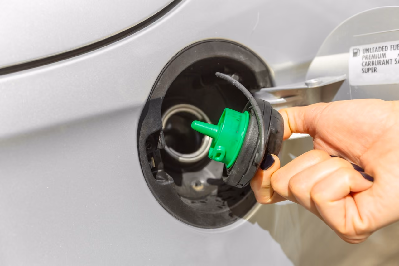 Hand opening a car's fuel cap to check the fuel system