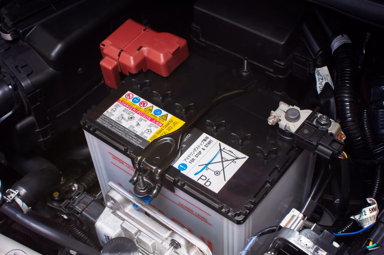 Car battery and terminals in an engine bay during an auto electrical repair