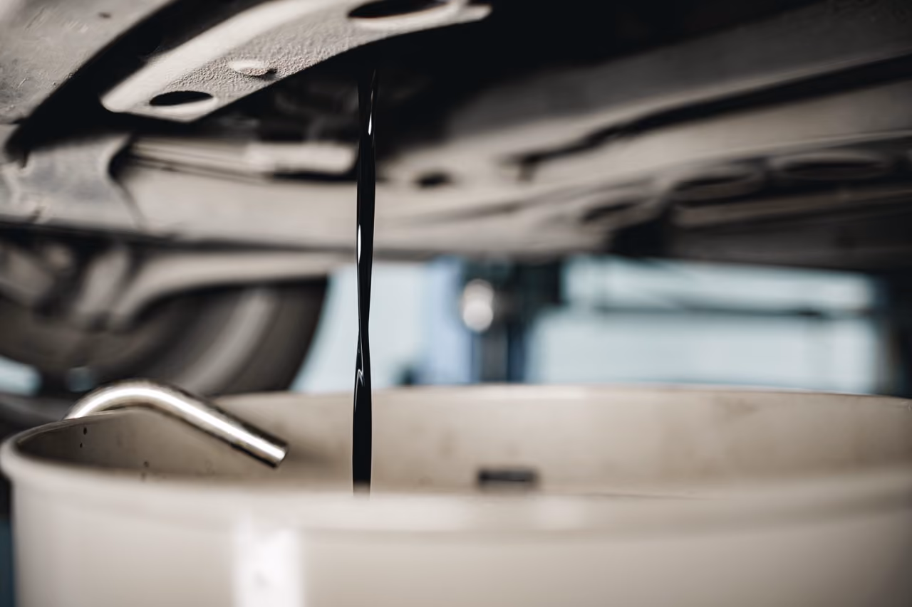 Old engine oil draining from a car during a full car service