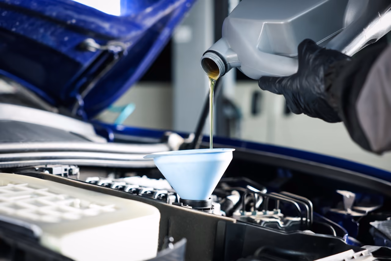 Mechanic topping up engine oil through a funnel during a full car service