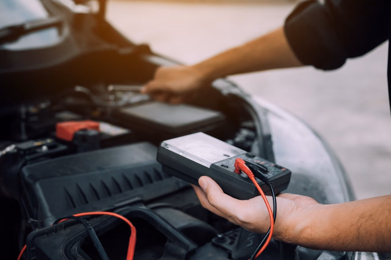 Mechanic testing a car battery with a multimeter during a mobile service