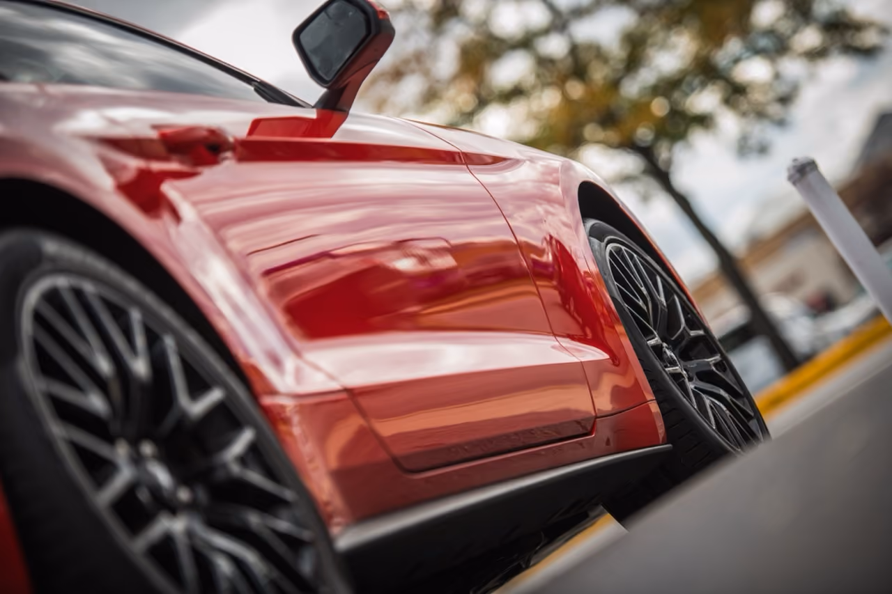 Red car's bodywork and alloy wheel checked during a standard pre-purchase inspection