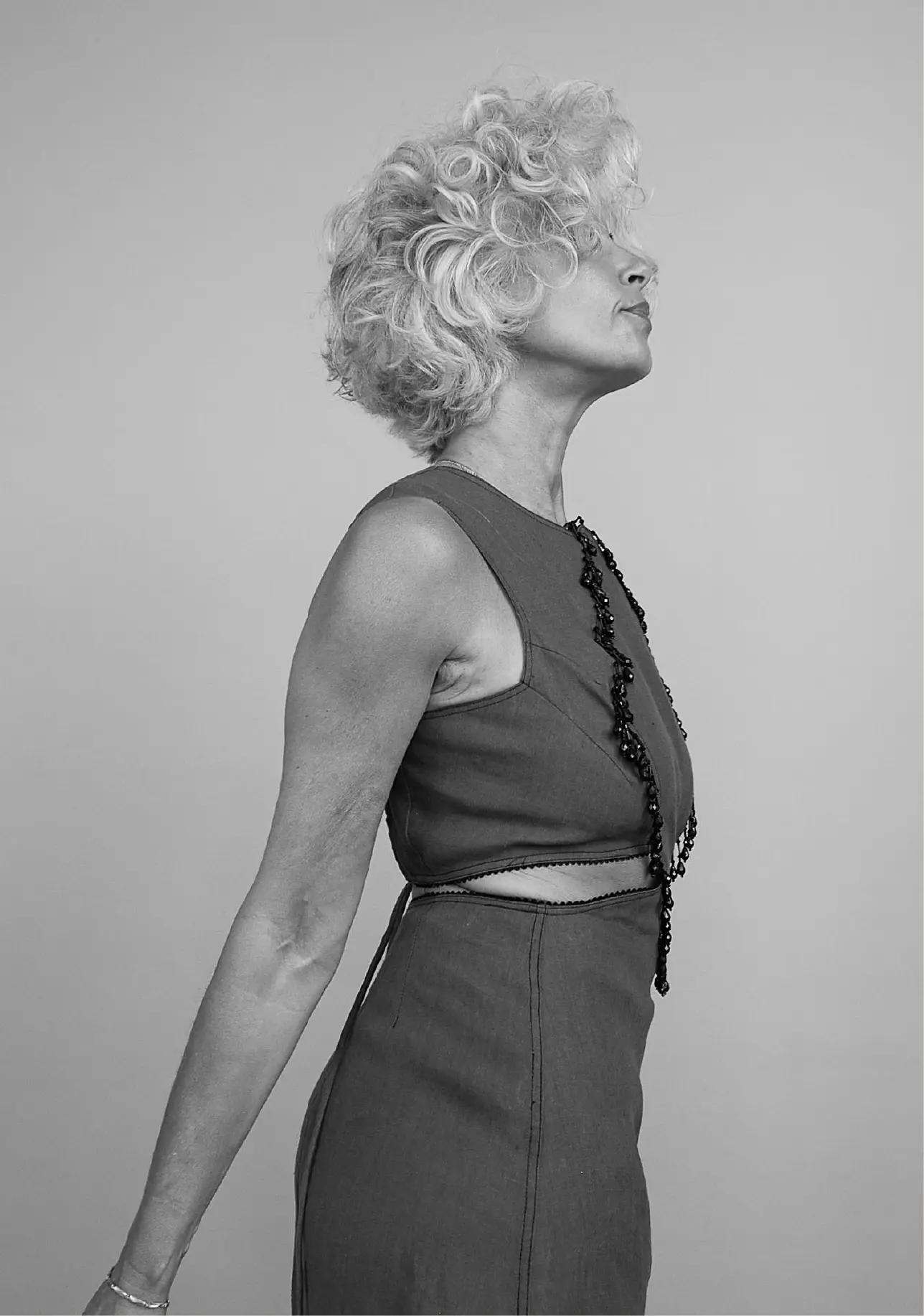 A middle aged woman with short and curly hair looking on the side