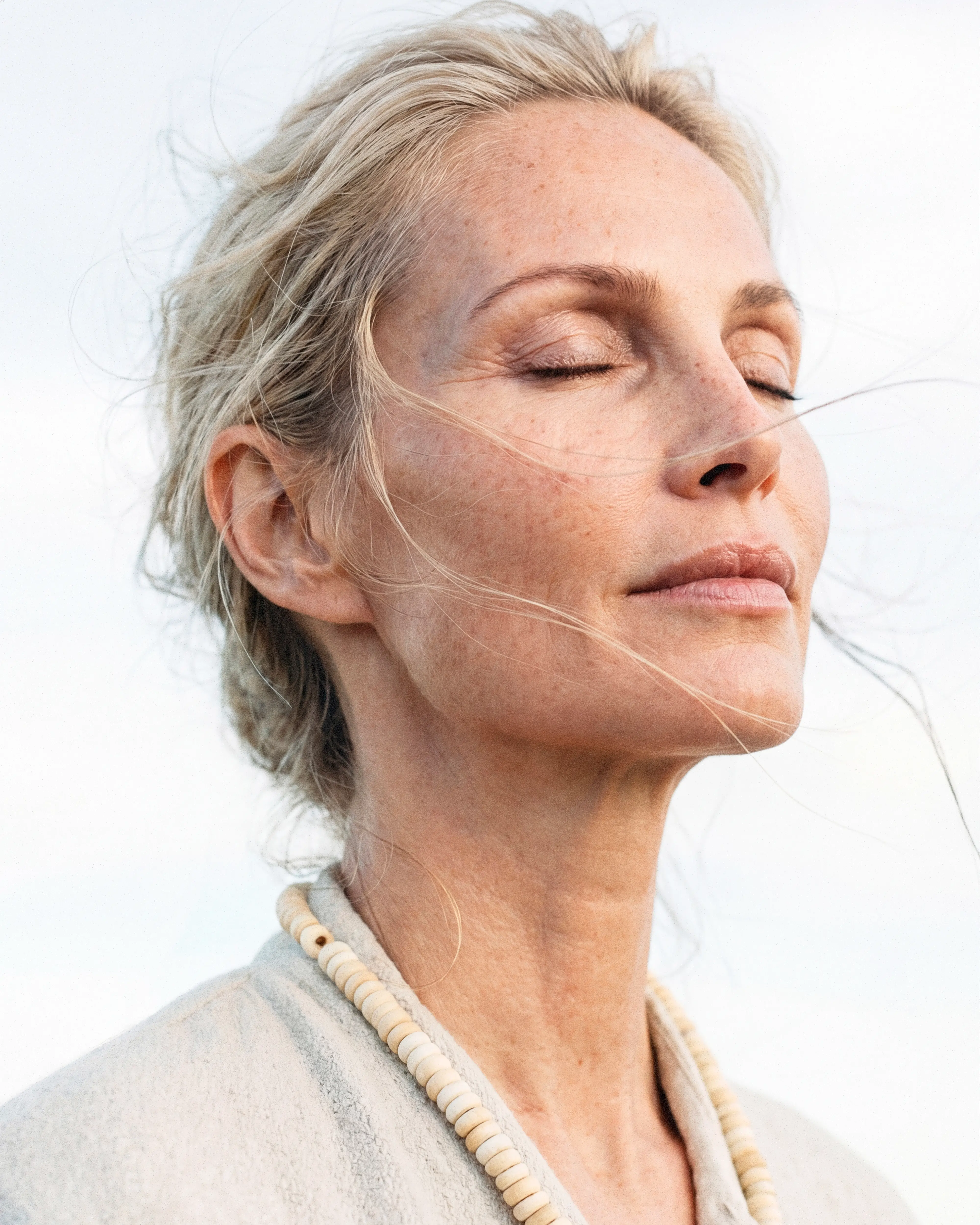 A middle aged good looking blonde woman with close eyes is breathing with a relaxed face.