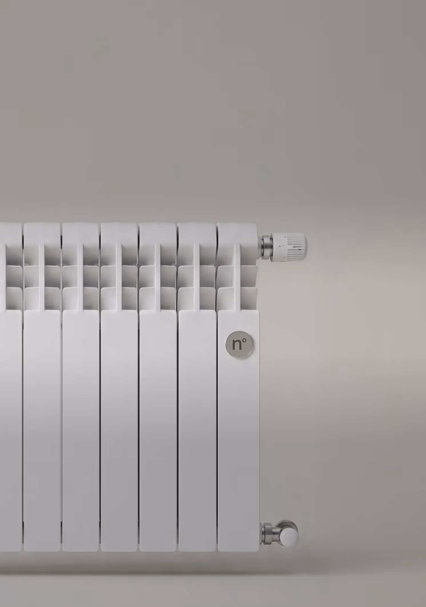 White modern radiator heater attached to a light gray wall with a temperature control knob.