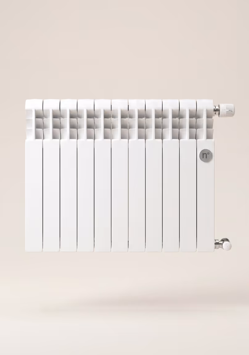 White modern radiator with multiple vertical panels mounted on a beige wall with control valves.