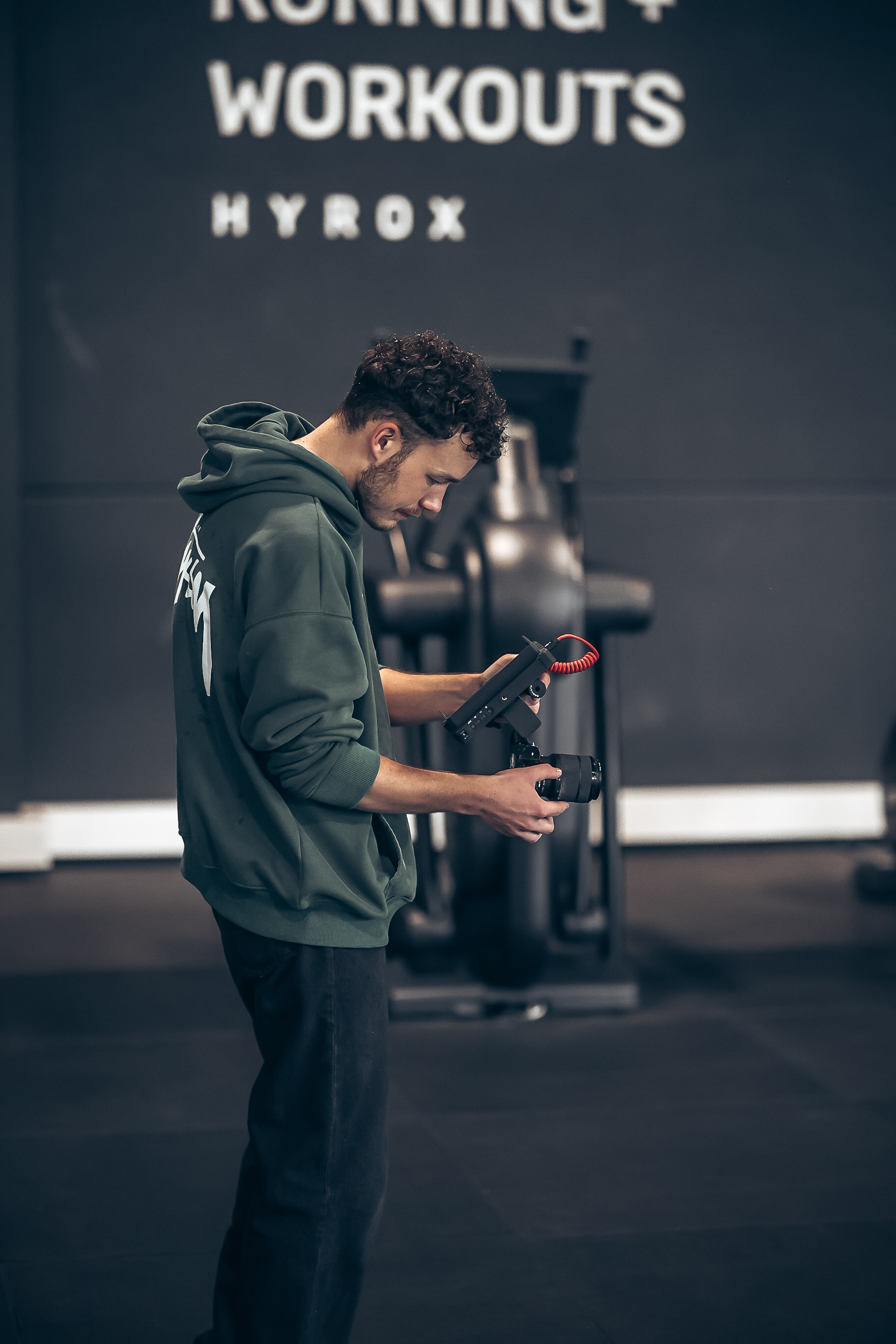 Fotograf mit Kamera vor der Hyrox-Wand eines Fitnessstudios