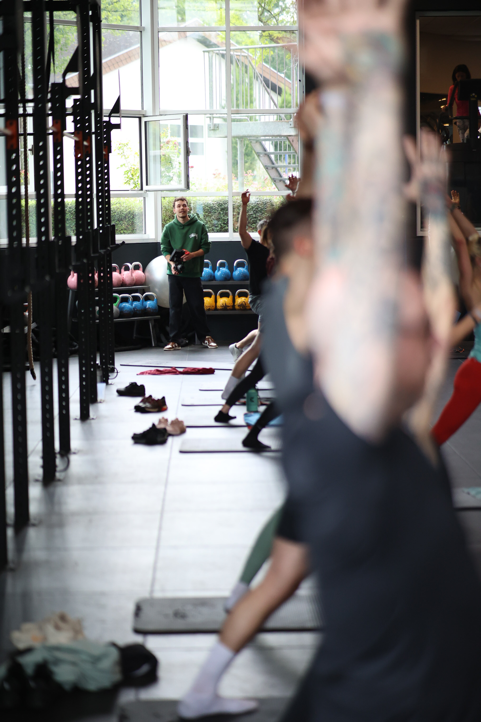Trainer leitet einen Gruppenkurs im Fitnessstudio, Teilnehmende auf Matten
