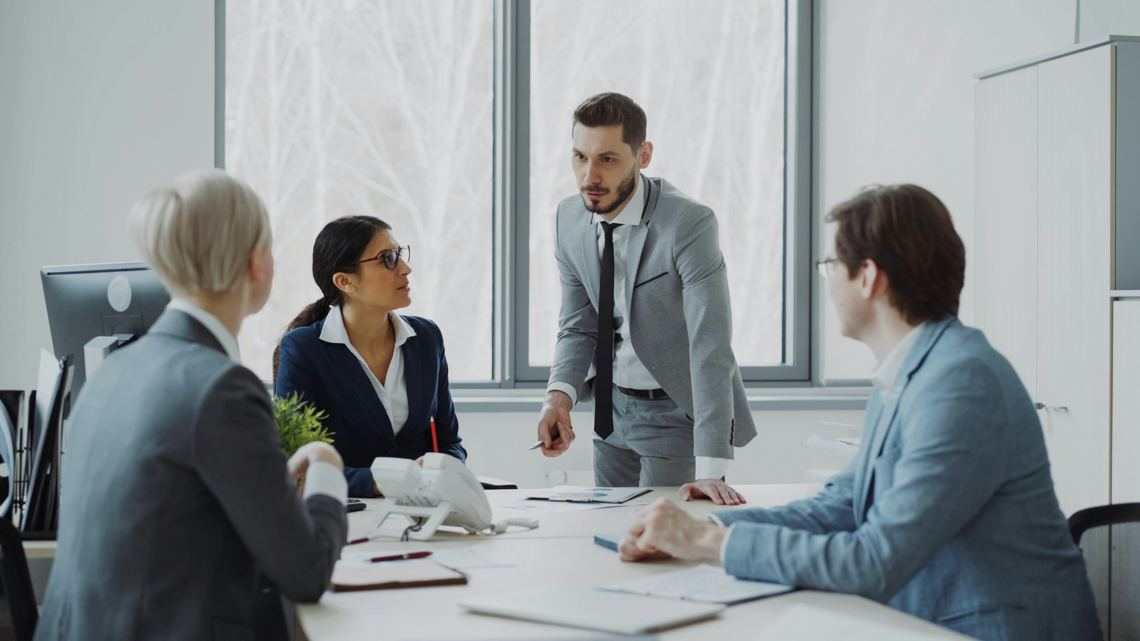 Four people from a professional services company having a formal meeting in the office.