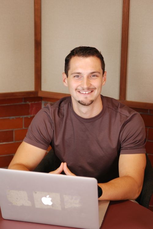 A portrait photo of Harry Wintour, the founder of Whitecross Digital, smiling in front of a forest background.