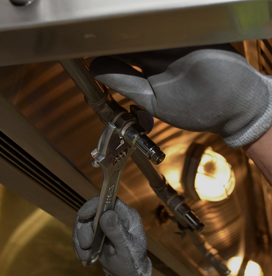 Technician tightening a pipe fitting with a wrench