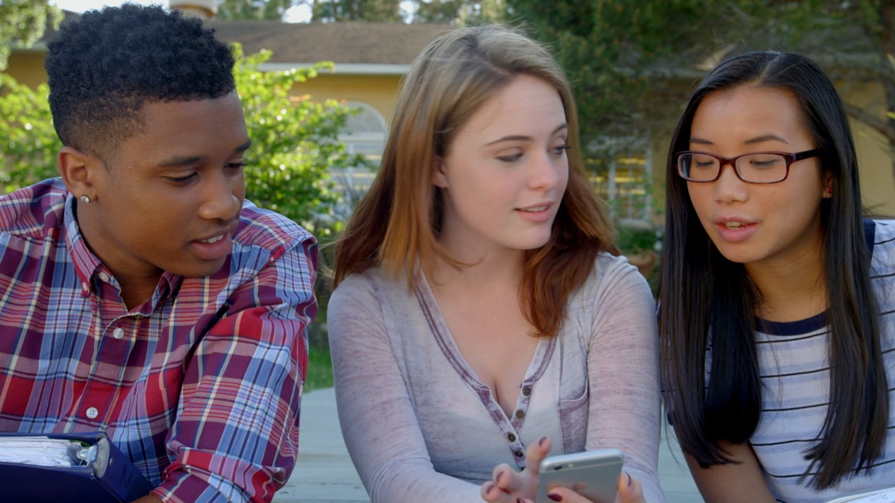 Three students gathered around a phone in the StudyAce product launch video