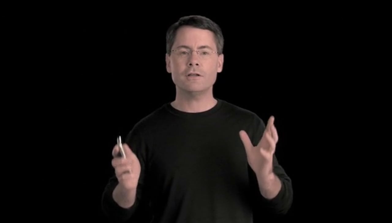 Presenter holding an iPhone against a black background in Apple’s guided tour