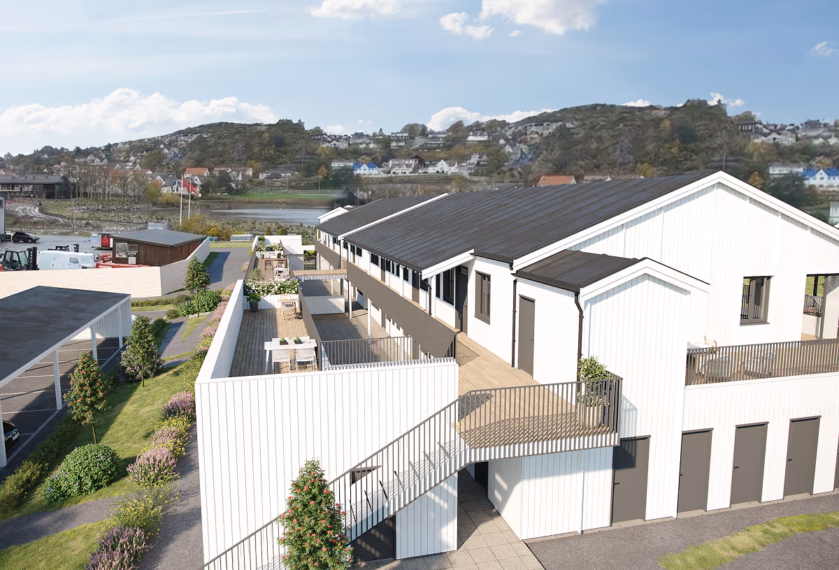 Modern white residential building with rooftop terraces and outdoor seating overlooking a hilly town.