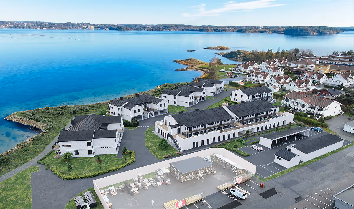 Residential neighborhood with modern houses near a calm blue body of water and green landscape.