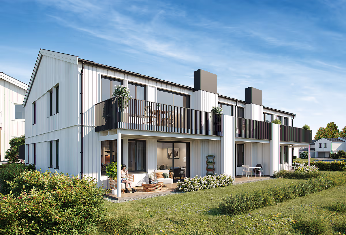 Modern white two-story townhouses with balconies, patios, and green lawn under a blue sky.