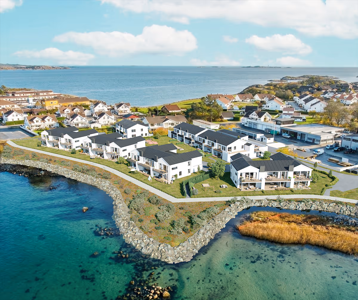 Coastal residential neighborhood with modern white houses and clear blue water under a partly cloudy sky.